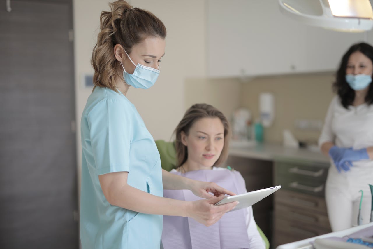 Dental professional consulting with patient using a tablet in a modern clinic setting.